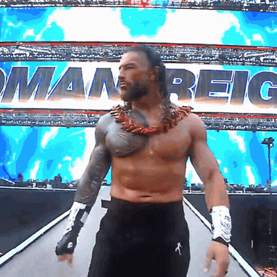 Shirtless Wrestler Walking Down Ramp With Roman Reigns Behind Him GIF