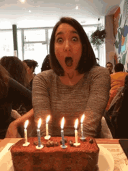 Shocked Woman Blowing Birthday Candles GIF