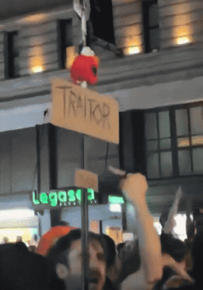 Sign Saying Traitor Hanging From Pole GIF