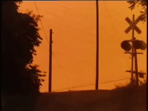 Silhouette Of Person Next To Railroad Crossing GIF