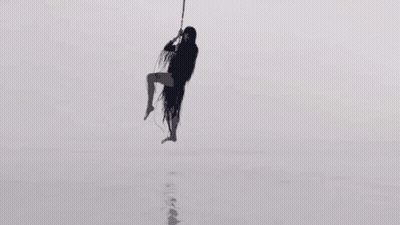 Silhouette Of Woman Hanging From Rope In Sky GIF