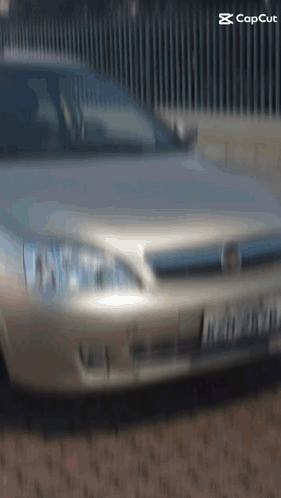 Silver Car Parked In Front Of Fence With Capcut GIF