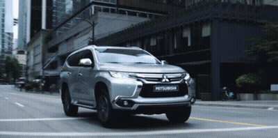 Silver Mitsubishi SUV Driving On City Street GIF