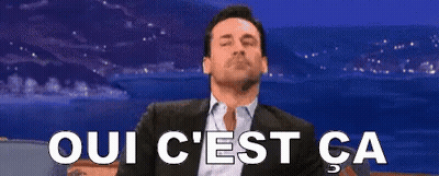 Sitting Man In Suit With Oui C'est Ca Sign GIF