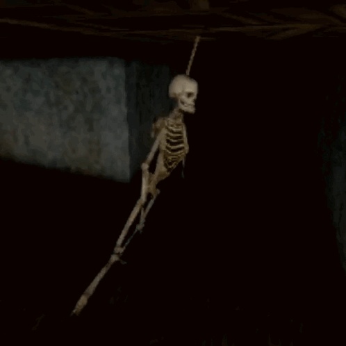 Skeleton Hanging From Ceiling In Dark Cave GIF