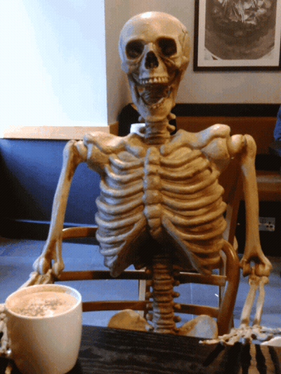 Skeleton Sitting At Table With Coffee GIF