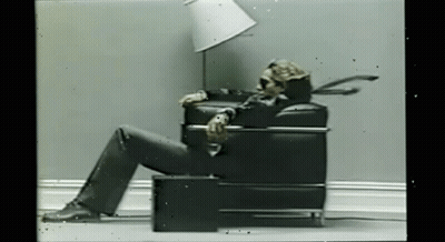 Skeleton Sitting In Chair With Lamp On Head GIF