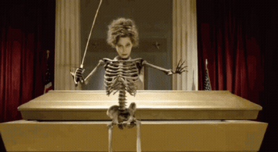 Skeleton Sitting In Coffin Holding Baton GIF
