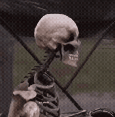 Skeleton Sitting In Front Of Black Tent GIF