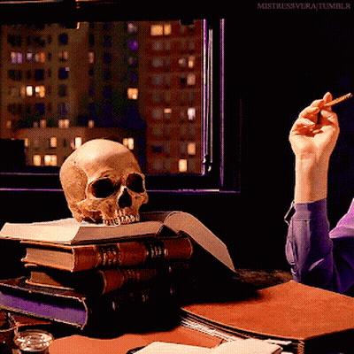 Skull On Stack Of Books And Hand Holding Cigarette GIF
