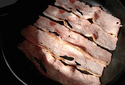 Slices Of Bacon Are Cooking In A Skillet GIF