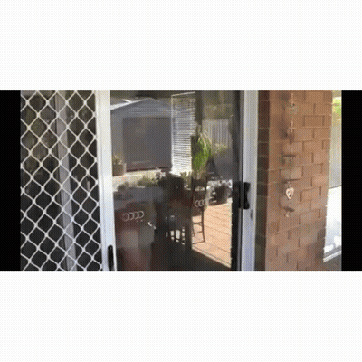 Sliding Glass Door Open To Patio With Brick Wall And Table And Chairs GIF