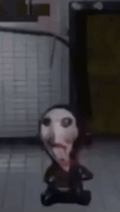 Small Doll With Bloody Face Sitting On Floor GIF