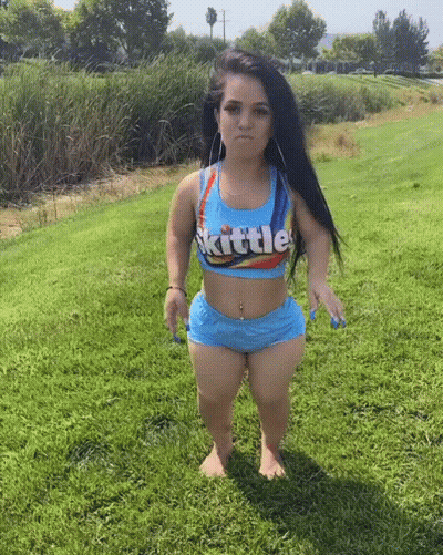 Small Woman In Skittles Outfit Standing In Grass GIF