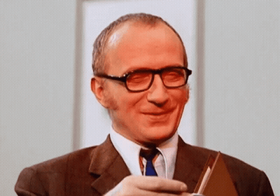Smiling Man In Glasses And Suit Holding Book GIF
