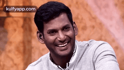 Smiling Man In Gray Sweater Sitting GIF