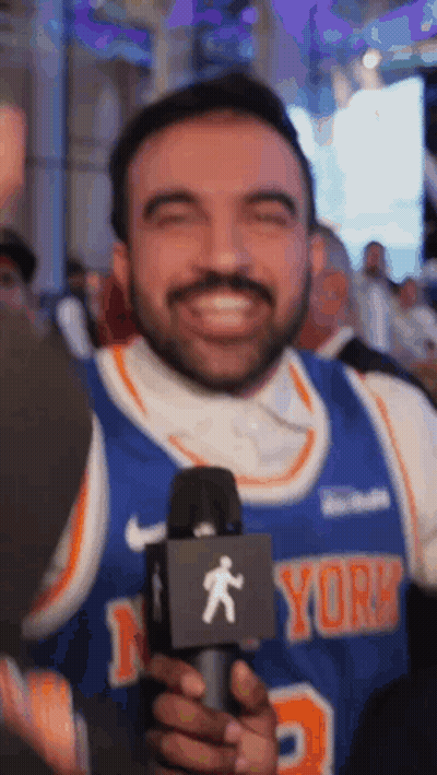 Smiling Man In New York Knicks Jersey Holding Microphone GIF