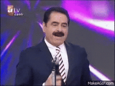 Smiling Man In Suit And Tie Holding Microphone GIF