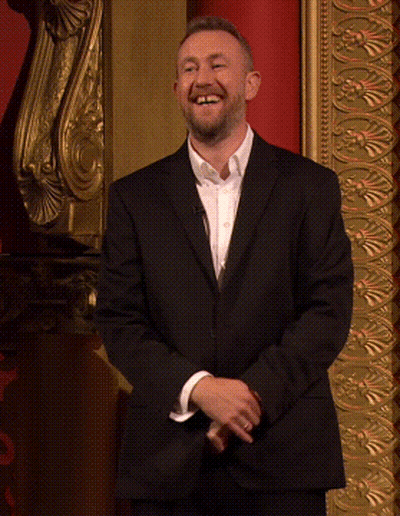 Smiling Man In Suit Before Gold Wall GIF