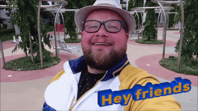 Smiling Man With Glasses And Hat Saying Hey Friends GIF