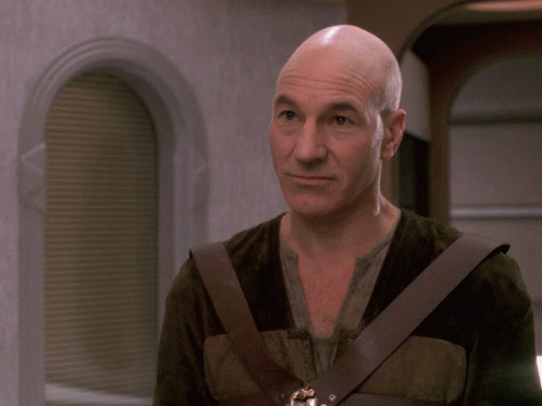 Smiling Man With Shaved Head And Brown Vest GIF