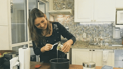 Smiling Woman Pouring Liquid Into Pan GIF