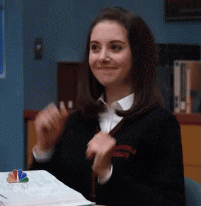 Smiling Woman Sitting At Desk With Book GIF