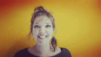 Smiling Woman With Bun In Front Of Yellow Wall GIF