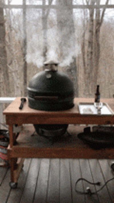 Smoke Is Coming Out Of A Big Green Egg On A Wooden Table GIF