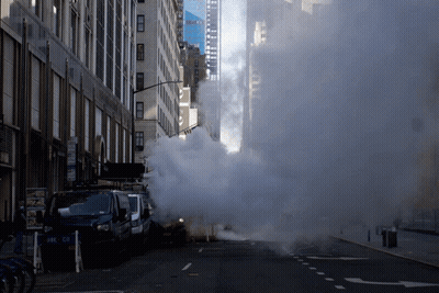 Smoke Is Coming Out Of A Drain On The Side Of The Road GIF