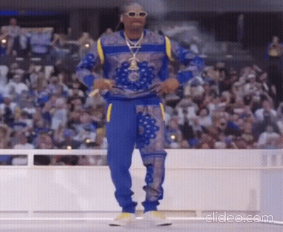 Snoop Dogg Is Dancing On A Stage In Front Of A Crowd At A Basketball Game . GIF