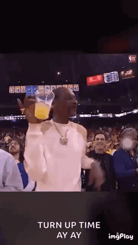 Snoop Dogg Is Holding A Cup Of Orange Juice In A Crowd Of People . GIF
