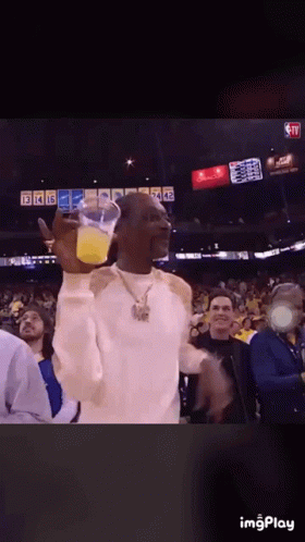 Snoop Dogg Is Holding A Cup Of Orange Juice In Front Of A Crowd GIF