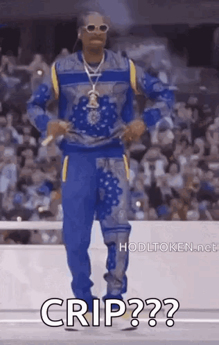 Snoop Dogg Is Wearing A Blue Sweater And Blue Pants While Standing On A Stage . GIF