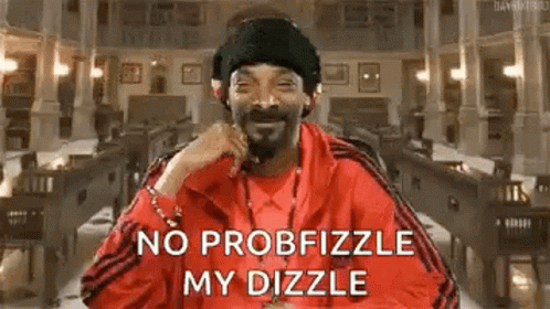 Snoop Dogg Is Wearing A Red Jacket And A Black Hat While Sitting In Front Of A Building . GIF