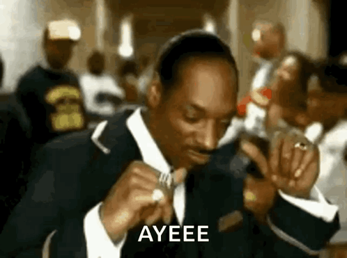 Snoop Dogg Is Wearing A Suit And Tie And Is Holding A Ring In His Hand . GIF