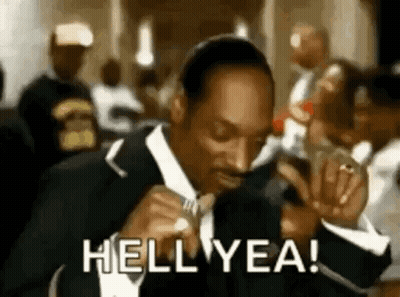 Snoop Dogg Is Wearing A Suit And Tie And Smoking A Cigarette In A Crowd . GIF