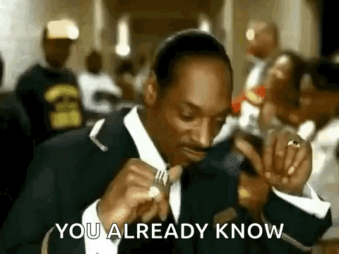 Snoop Dogg Is Wearing A Suit And Tie While Eating A Piece Of Food . GIF