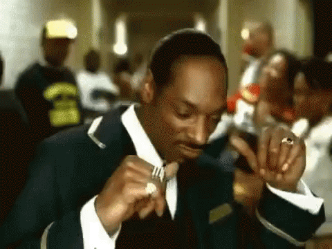 Snoop Dogg Is Wearing A Suit And Tie While Holding A Ring In His Hand . GIF