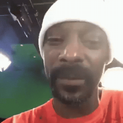 Snoop Dogg Is Wearing A White Hat And An Orange Shirt While Making A Funny Face . GIF