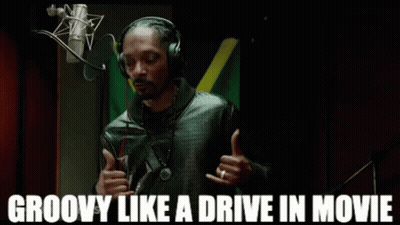 Snoop Dogg Is Wearing Headphones In Front Of A Microphone And Giving A Thumbs Up . GIF