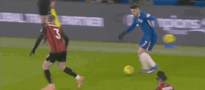 Soccer Player In Blue Jersey Kicking Ball While Red Shirt Watches GIF