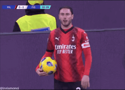 Soccer Player in Red Emirates Fly Bet Jersey Holding Yellow Ball