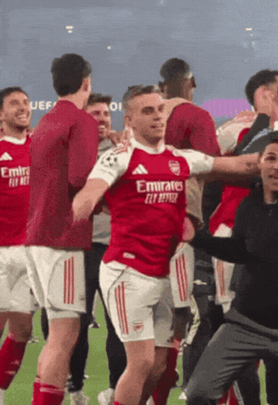 Soccer Player In Red Emirates Jersey Surrounded By Teammates GIF