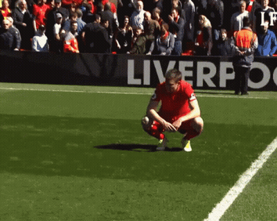 Soccer Player Kneeling In Front Of Liverpool Sign GIF