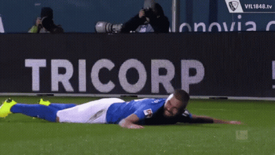 Soccer Player Laying On Field In Front Of Tricorp Banner GIF