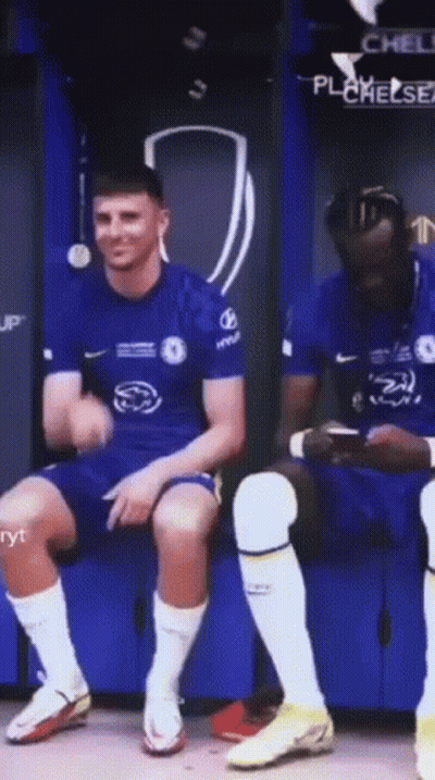 Soccer Player Sitting On Bench While Teammate Looks At Phone GIF