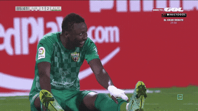 Soccer Player Stretching Legs In Front Of Coca Cola Sign GIF