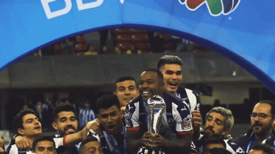 Soccer Players Celebrate With Trophy In Front Of BB Banner GIF