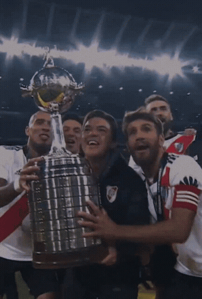 Futbolistas sosteniendo trofeo juntos GIF